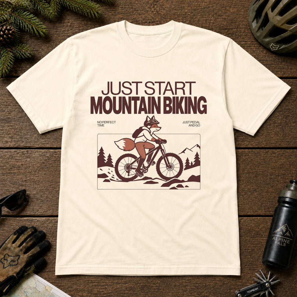 Natural tee featuring a fox mountain biking through a minimalist trail scene with the phrases “Just Start Mountain Biking,” “No Perfect Time,” and “Just Pedal and Go.”