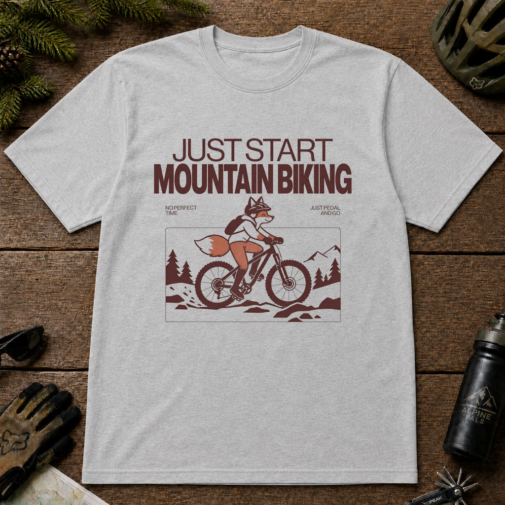 Sport Grey tee featuring a fox mountain biking through a minimalist trail scene with the phrases “Just Start Mountain Biking,” “No Perfect Time,” and “Just Pedal and Go.”