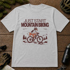 Sport Grey tee featuring a fox mountain biking through a minimalist trail scene with the phrases “Just Start Mountain Biking,” “No Perfect Time,” and “Just Pedal and Go.”
