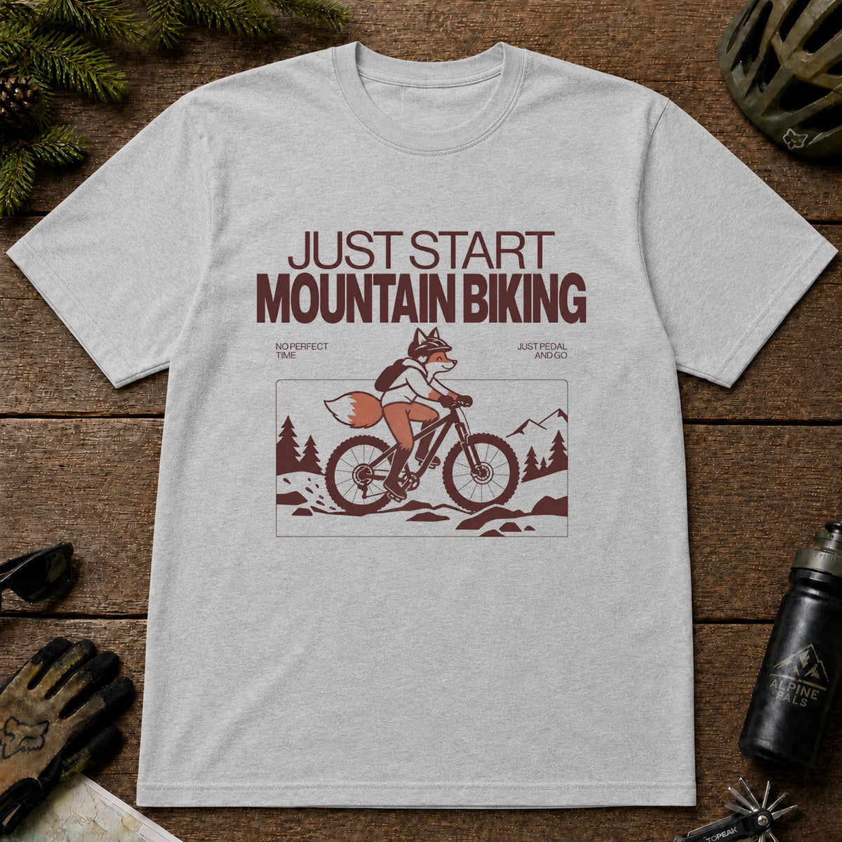 Sport Grey tee featuring a fox mountain biking through a minimalist trail scene with the phrases “Just Start Mountain Biking,” “No Perfect Time,” and “Just Pedal and Go.”