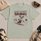 Bay tee featuring a moose skiing through a minimalist mountain scene with the phrases “Just Start Skiing,” “No Perfect Time,” and “Just Click In and Go.”