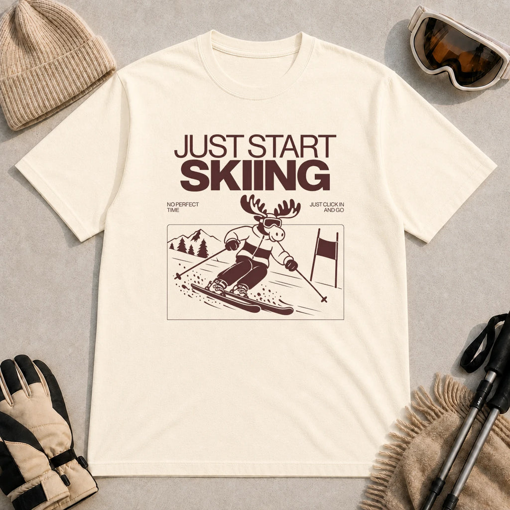 Natural tee featuring a moose skiing through a minimalist mountain scene with the phrases “Just Start Skiing,” “No Perfect Time,” and “Just Click In and Go.”