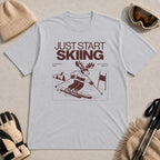 Sport Grey tee featuring a moose skiing through a minimalist mountain scene with the phrases “Just Start Skiing,” “No Perfect Time,” and “Just Click In and Go.”