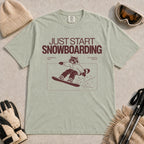 Bay tee featuring a raccoon snowboarding through a minimalist slope scene with the phrases “Just Start Snowboarding,” “No Perfect Time,” and “Just Strap In and Go.”