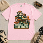 Blossom tee featuring a relaxed raccoon enjoying a burger and fries at a mountain lodge table above the phrase “Personal Best: 11:37 Lunch.”
