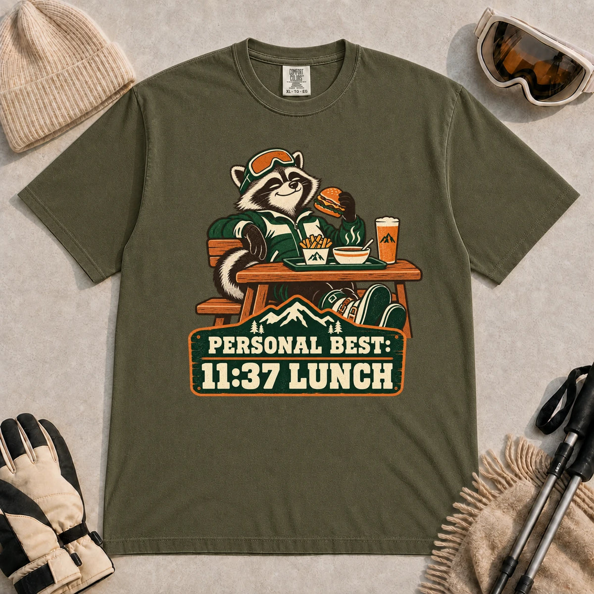 Hemp tee featuring a relaxed raccoon enjoying a burger and fries at a mountain lodge table above the phrase “Personal Best: 11:37 Lunch.”