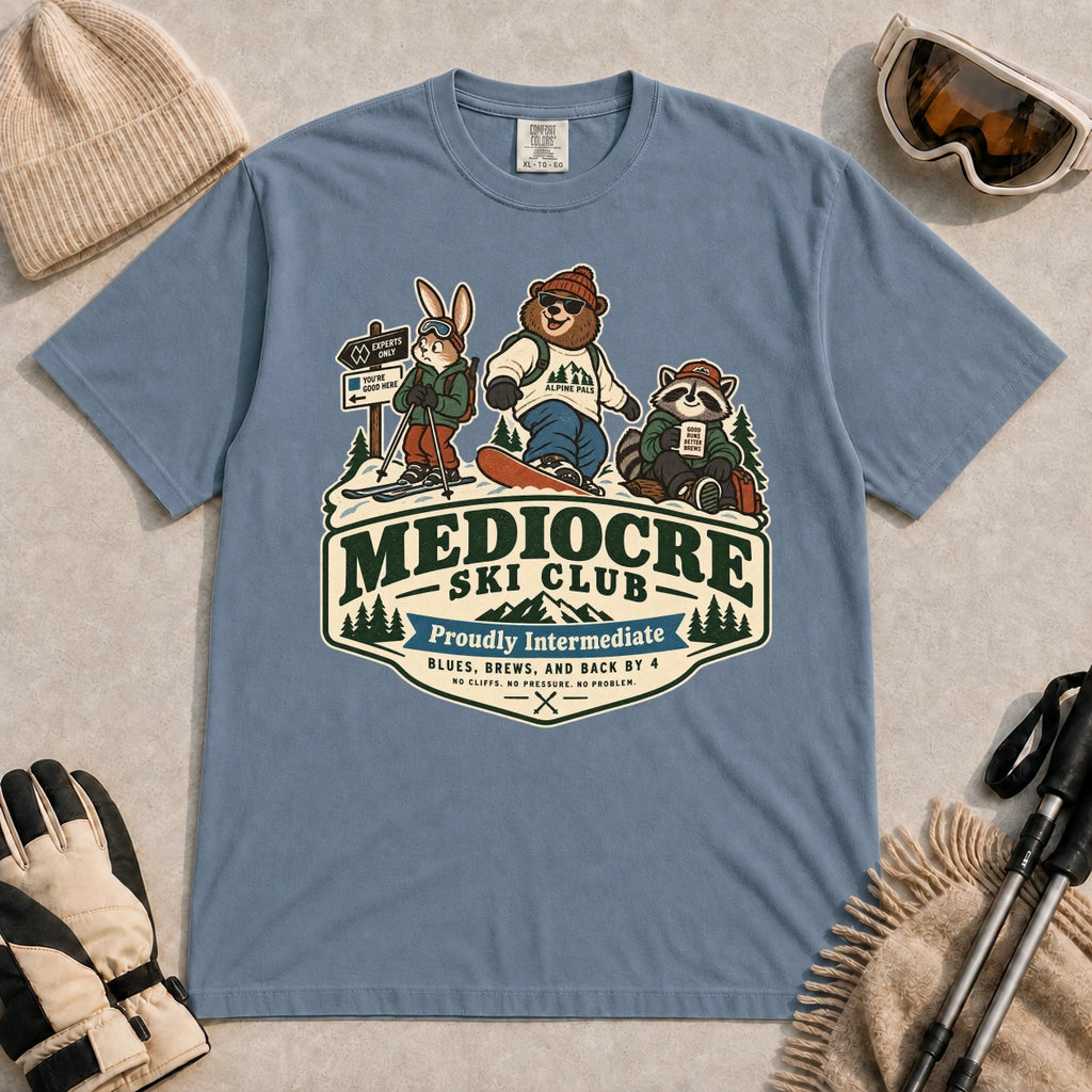 Blue Jean tee featuring a bear, bunny, and raccoon in ski gear above a retro “Mediocre Ski Club” badge with the phrases “Proudly Intermediate” and “Blues, Brews, and Back by 4.”