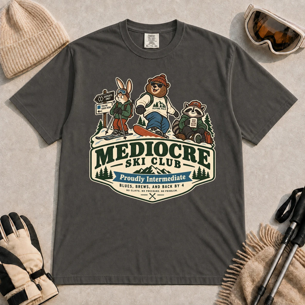 Pepper tee featuring a bear, bunny, and raccoon in ski gear above a retro “Mediocre Ski Club” badge with the phrases “Proudly Intermediate” and “Blues, Brews, and Back by 4.”