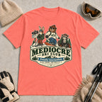 Coral Silk tee featuring a bear, bunny, and raccoon in ski gear above a retro “Mediocre Ski Club” badge with the phrases “Proudly Intermediate” and “Blues, Brews, and Back by 4.”