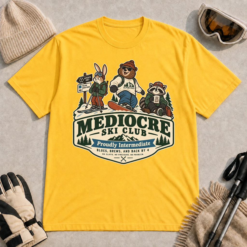 Daisy tee featuring a bear, bunny, and raccoon in ski gear above a retro “Mediocre Ski Club” badge with the phrases “Proudly Intermediate” and “Blues, Brews, and Back by 4.”