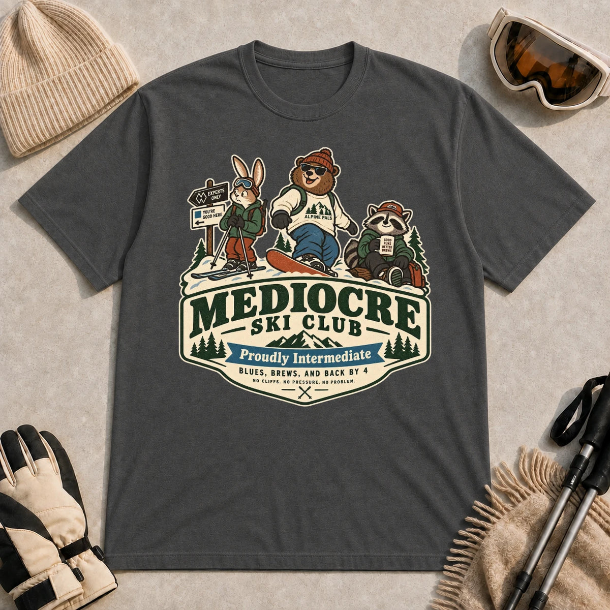 Dark Heather Gray tee featuring a bear, bunny, and raccoon in ski gear above a retro “Mediocre Ski Club” badge with the phrases “Proudly Intermediate” and “Blues, Brews, and Back by 4.”