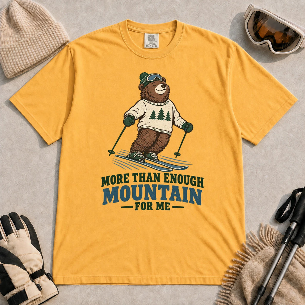 Mustard tee featuring a smiling bear skiing in retro mountain gear above the phrase “More Than Enough Mountain for Me.”