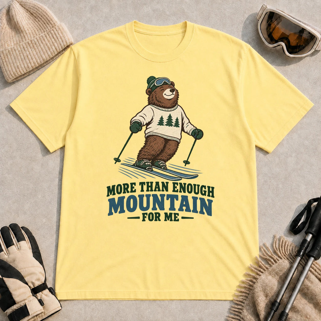 Cornsilk tee featuring a smiling bear skiing in retro mountain gear above the phrase “More Than Enough Mountain for Me.”