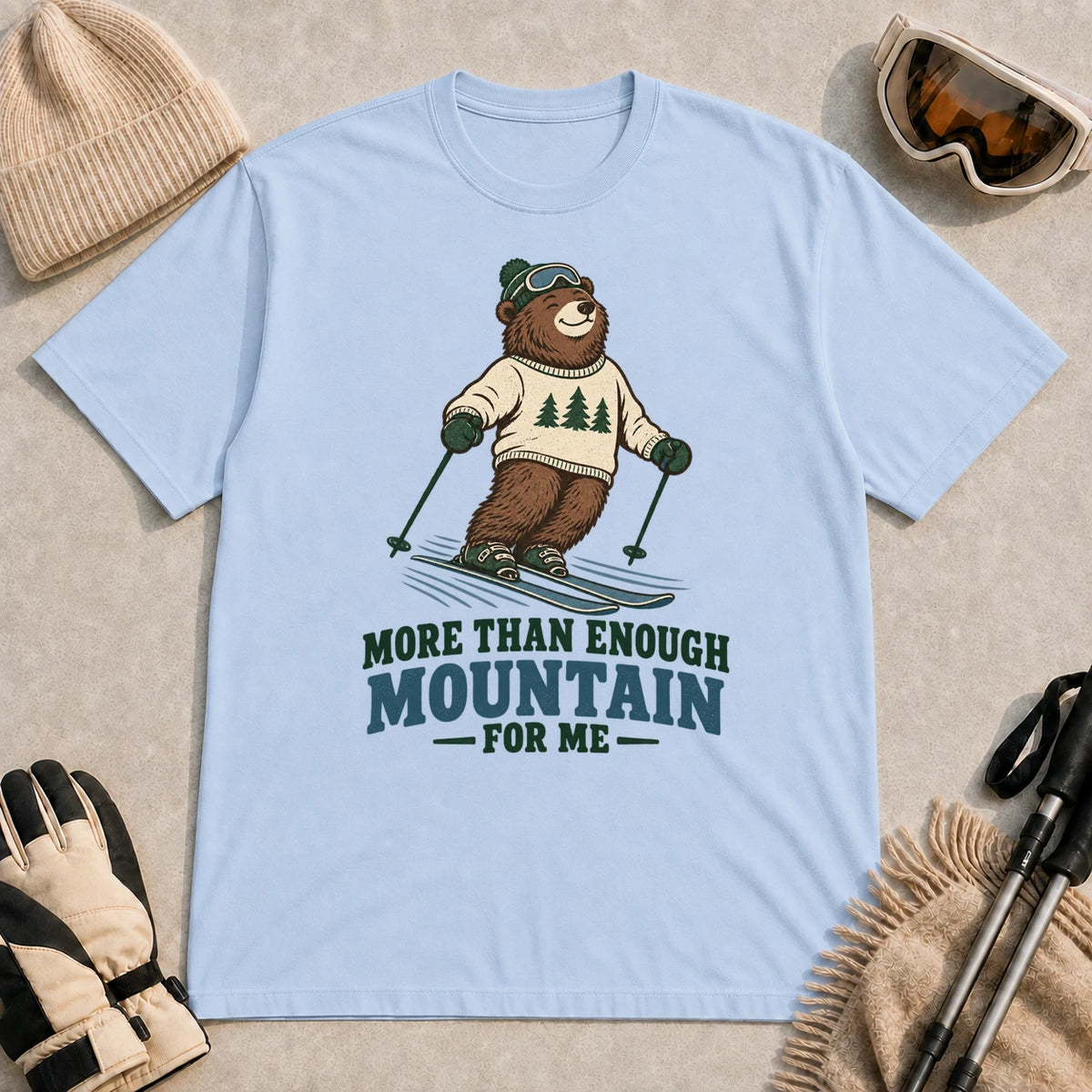 Light Blue tee featuring a smiling bear skiing in retro mountain gear above the phrase “More Than Enough Mountain for Me.”