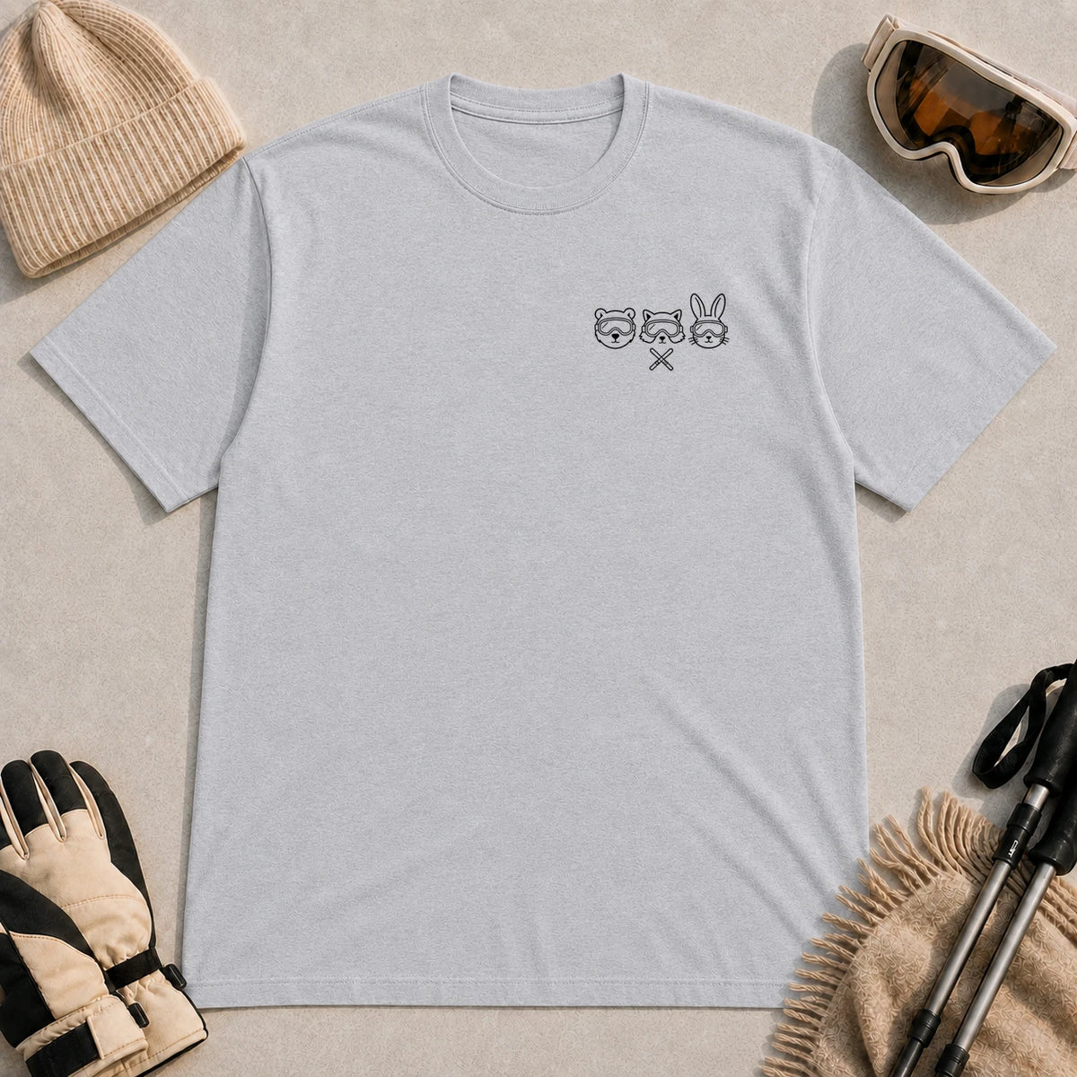 Sport Grey tee featuring minimalist black line art of a bear, raccoon, and bunny wearing ski goggles above a small pair of crossed skis.