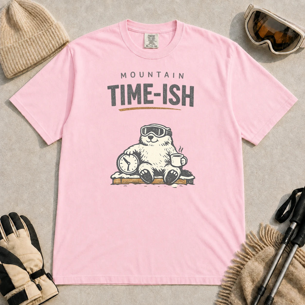 Blossom tee featuring a relaxed bear in ski goggles sitting with a steaming mug and clock on a snowy bench, with the phrase “Mountain Time-ish.”