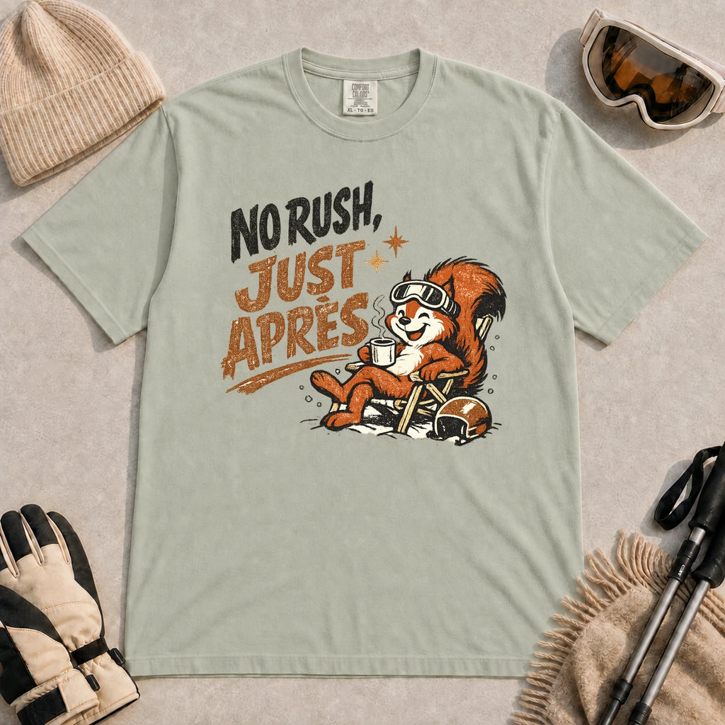 Bay tee featuring a cheerful squirrel in ski goggles relaxing in a chair with a hot drink and helmet, with the phrase “No Rush, Just Après.”