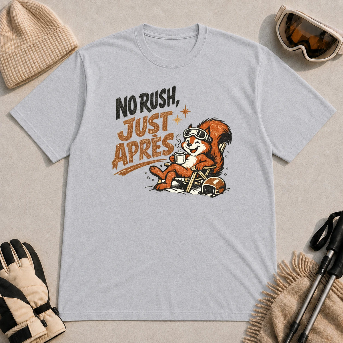 Sport grey tee featuring a relaxed squirrel in ski goggles lounging in a chair with a warm drink, paired with the phrase “No Rush, Just Après.”