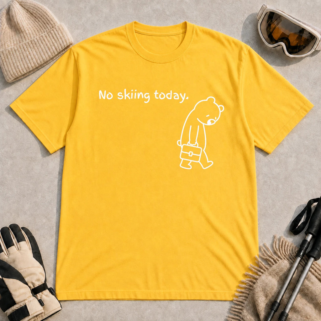 Daisy tee featuring a sad bear dressed for work and carrying a briefcase beneath the phrase “No skiing today.”