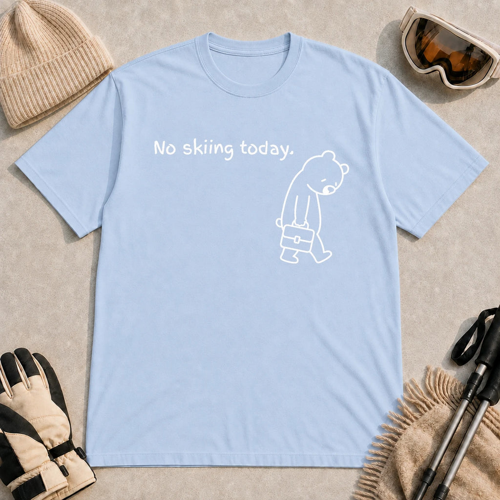 Light Blue tee featuring a sad bear dressed for work and carrying a briefcase beneath the phrase “No skiing today.”