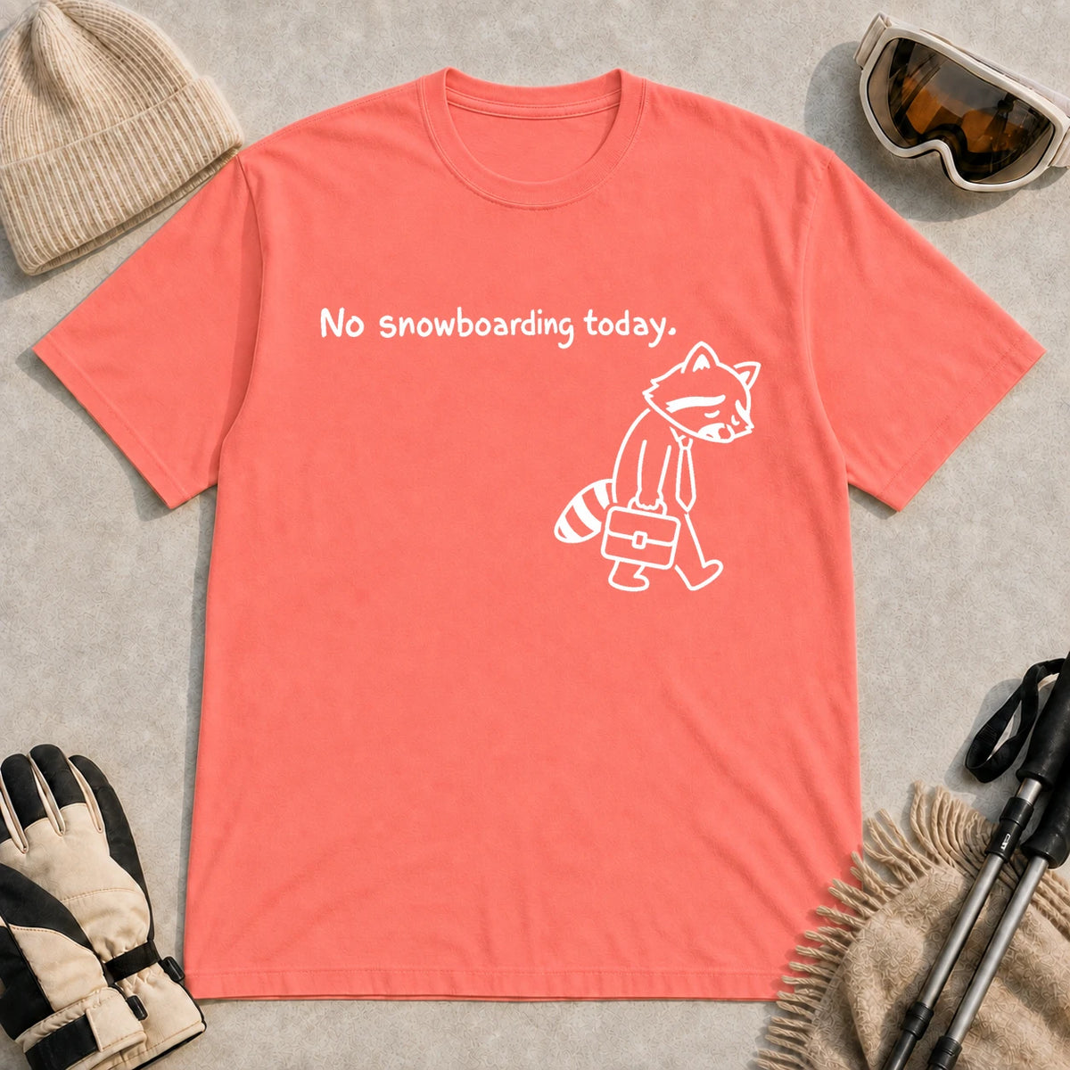 Coral Silk tee featuring a sad raccoon dressed for work and carrying a briefcase beneath the phrase “No snowboarding today.”