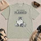 Bay tee featuring a raccoon in ski goggles sitting on a bench and studying a trail map beside a backpack, with the phrase “Not Much Planned.”