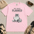 Blossom tee featuring a raccoon in ski goggles sitting on a bench and studying a trail map beside a backpack, with the phrase “Not Much Planned.”