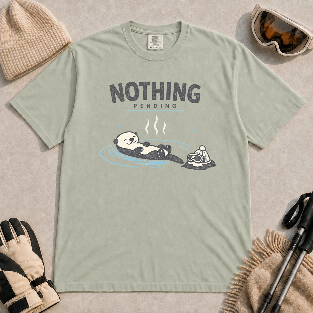 Bay tee featuring a relaxed otter soaking in a hot spring beside ski goggles and a beanie, with the phrase “Nothing Pending.”