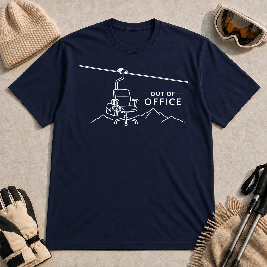 Navy tee featuring a minimalist white line-art chairlift carrying an office chair above mountain outlines beside the phrase “Out of Office.”