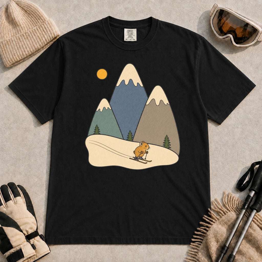 Black tee featuring a cute pika skiing beneath stylized snow-capped mountain peaks, evergreen trees, and a golden sun.