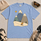 Washed Denim tee featuring a cute pika skiing beneath stylized snow-capped mountain peaks, evergreen trees, and a golden sun.