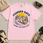 Blossom tee featuring a sunglasses-wearing otter snowboarding through powder beneath a mountain sunset, with the phrases “Powder Days” and “Chasin’ the Good Stuff.”
