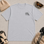 Sport Grey tee featuring minimalist black line art of a goggle-wearing dog beside an upright ski and ski boot.