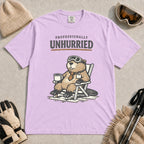 Orchid tee featuring a relaxed beaver in ski goggles sitting in a chair with a hot drink, with the phrase “Professionally Unhurried.”