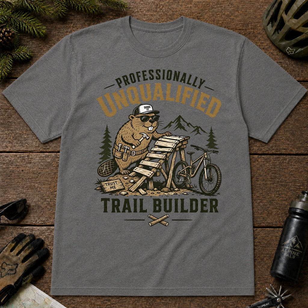 Graphite Heather tee featuring a sunglasses-wearing beaver building a wooden mountain bike ramp beside a bike, with the phrase “Professionally Unqualified Trail Builder.”