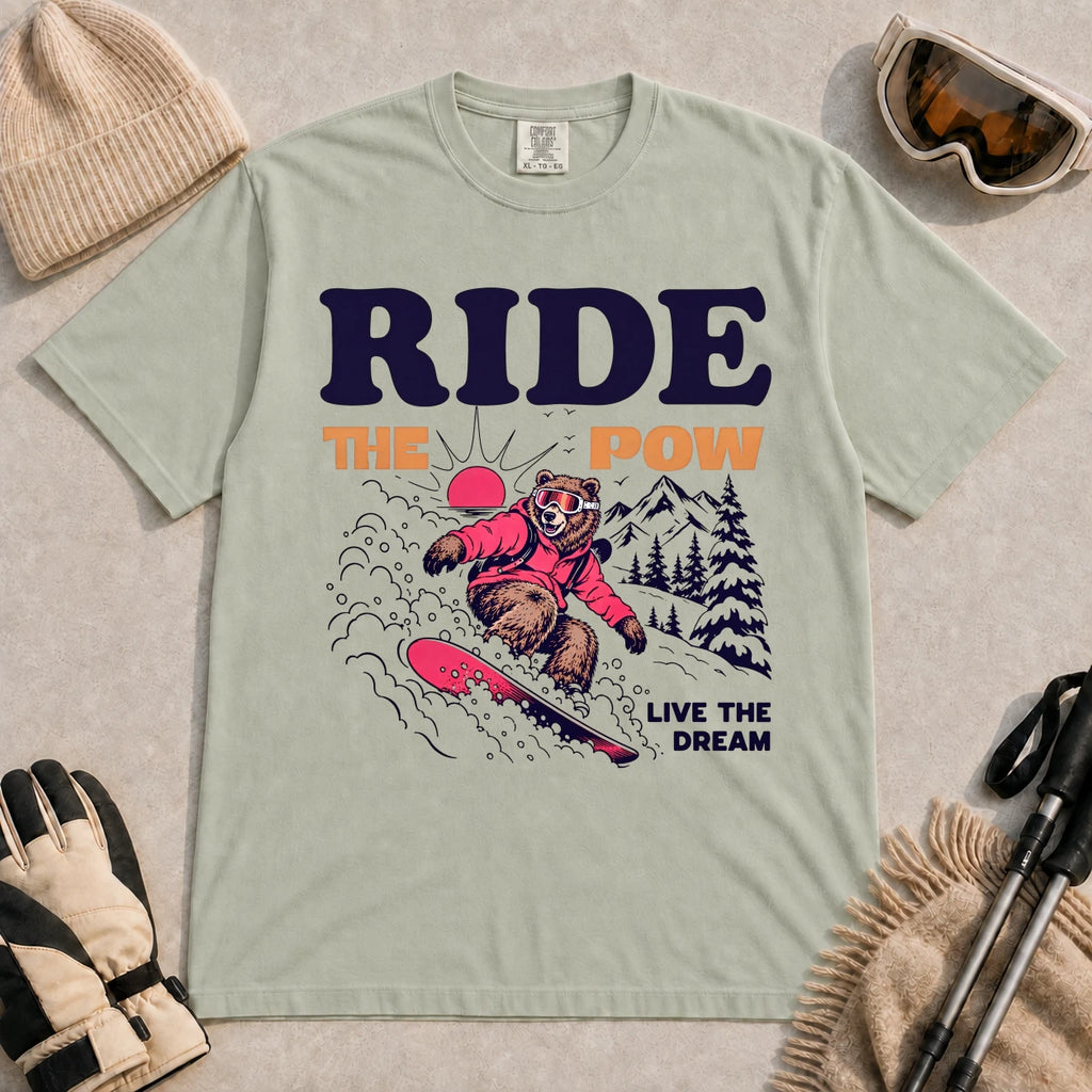 Bay tee featuring a bear snowboarding through powder in a retro mountain scene with the phrases “Ride the Pow” and “Live the Dream.”