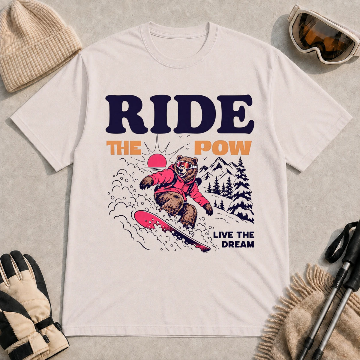 Ice Grey tee featuring a bear snowboarding through powder in a retro mountain scene with the phrases “Ride the Pow” and “Live the Dream.”