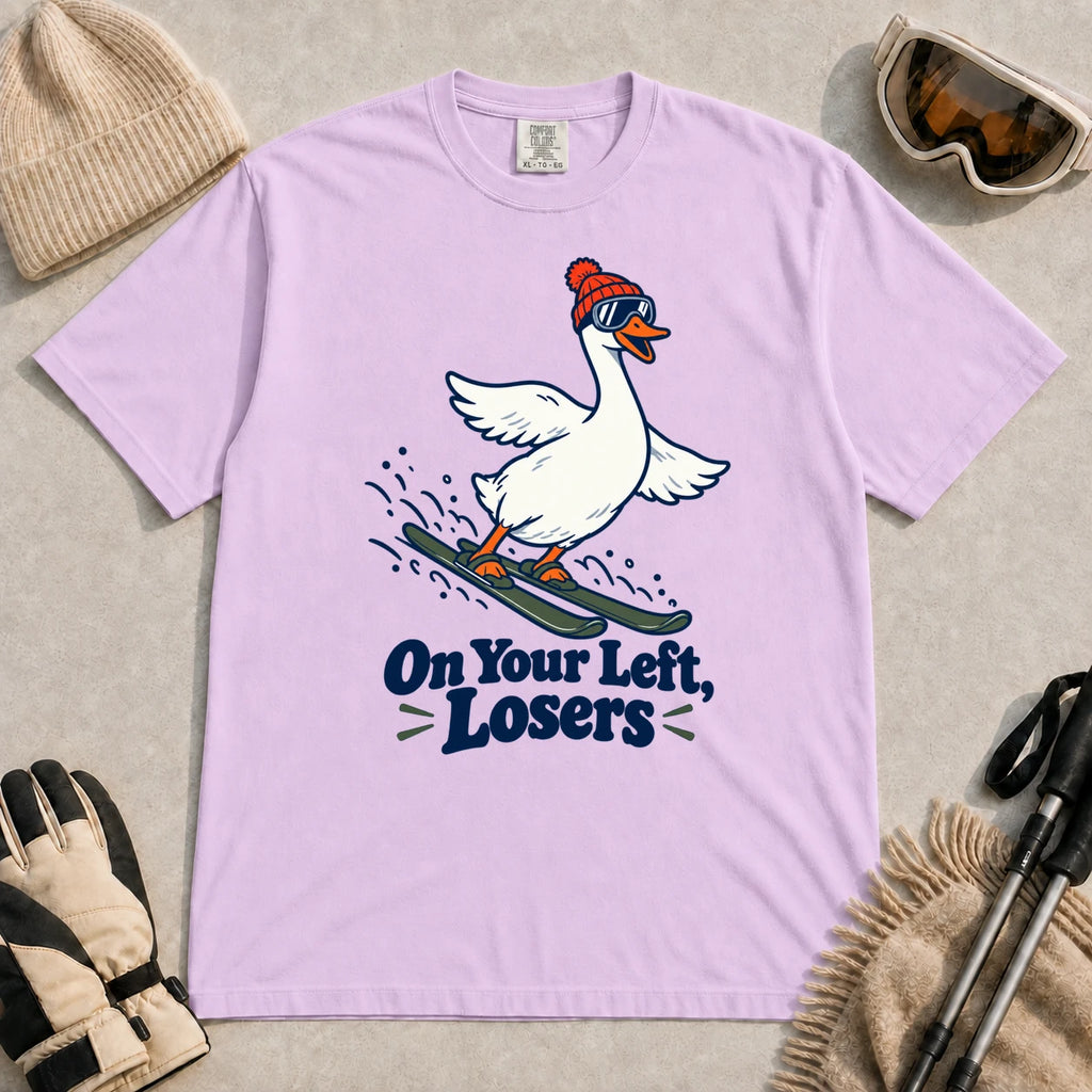 Orchid tee featuring a playful goose skiing in goggles and a beanie above the phrase “On Your Left, Losers.”