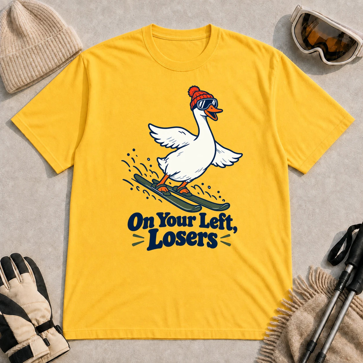 Daisy tee featuring a playful goose skiing in goggles and a beanie above the phrase “On Your Left, Losers.”