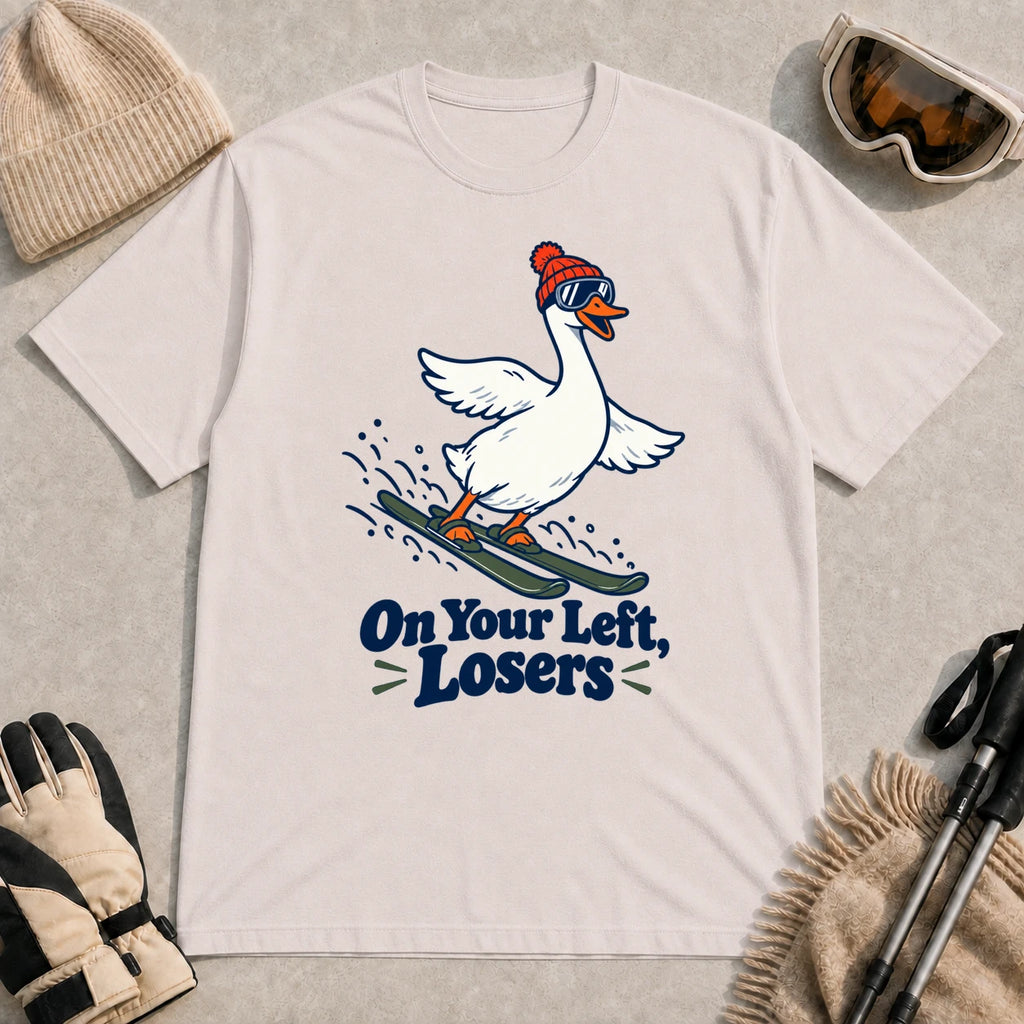 Ice Grey tee featuring a playful goose skiing in goggles and a beanie above the phrase “On Your Left, Losers.”