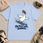 Light Blue tee featuring a playful goose skiing in goggles and a beanie above the phrase “On Your Left, Losers.”