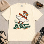 Ivory tee featuring a playful goose skiing in goggles and a beanie above the phrase “On Your Left, Losers.”