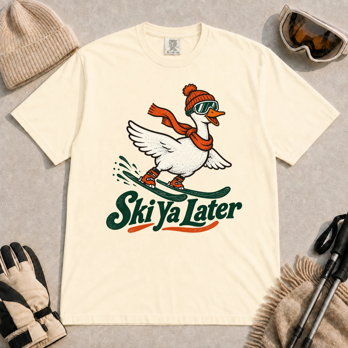 Ivory tee featuring a playful goose skiing in goggles and a beanie above the phrase “On Your Left, Losers.”