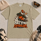 Khaki tee featuring a polar bear skiing through a spooky Halloween scene with a ghost and crescent moon above the phrase “Ski You in the Afterlife.”