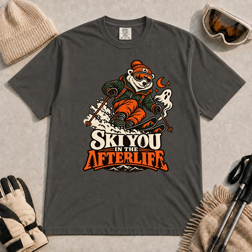 Pepper tee featuring a polar bear skiing through a spooky Halloween scene with a ghost and crescent moon above the phrase “Ski You in the Afterlife.”