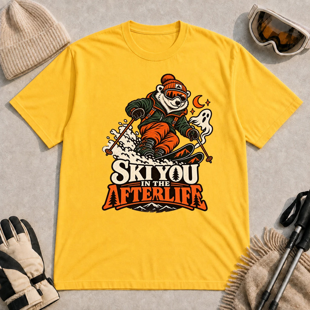 Daisy tee featuring a polar bear skiing through a spooky Halloween scene with a ghost and crescent moon above the phrase “Ski You in the Afterlife.”