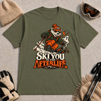 Military Green tee featuring a polar bear skiing through a spooky Halloween scene with a ghost and crescent moon above the phrase “Ski You in the Afterlife.”