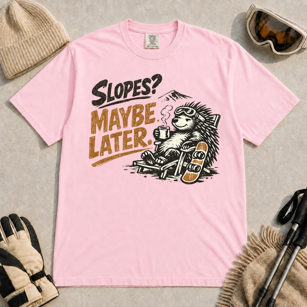 Blossom tee featuring a relaxed porcupine in ski goggles lounging in a chair with a hot drink beside a snowboard, with the phrase “Slopes? Maybe Later.”