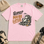 Blossom tee featuring a relaxed porcupine in ski goggles lounging in a chair with a hot drink beside a snowboard, with the phrase “Slopes? Maybe Later.”