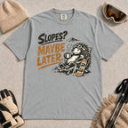 Granite tee featuring a relaxed porcupine in ski goggles lounging in a chair with a hot drink beside a snowboard, with the phrase “Slopes? Maybe Later.”